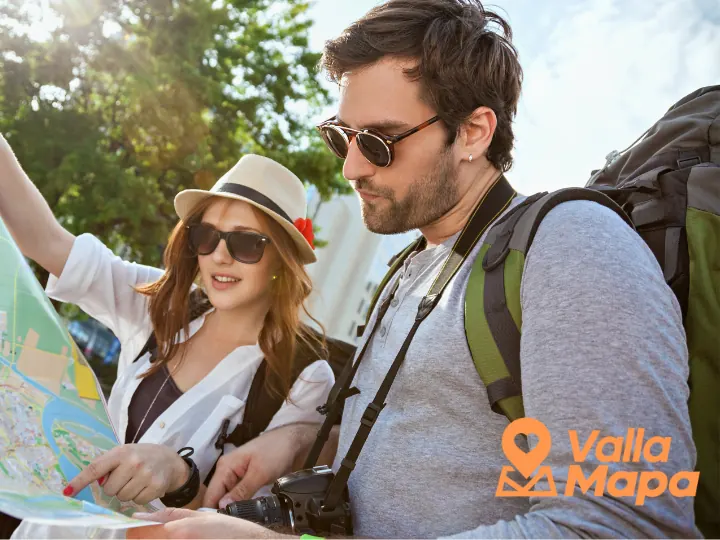 Two travelers with backpacks and sunglasses reading a paper map outdoors